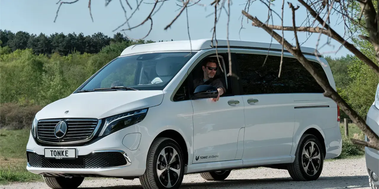 Vit eldriven husbil från Tonke parkerad på grusväg. En man med solglasögon sitter bakom ratten.