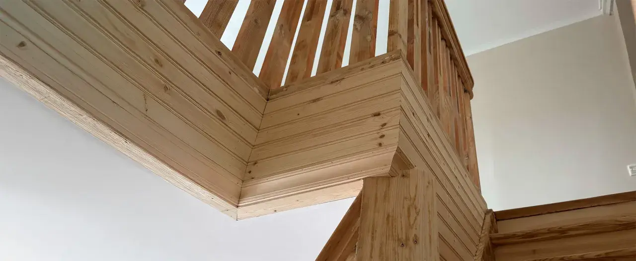 Detalles de la escalera con molduras de madera en la pared, creando un acabado rústico y acogedor.