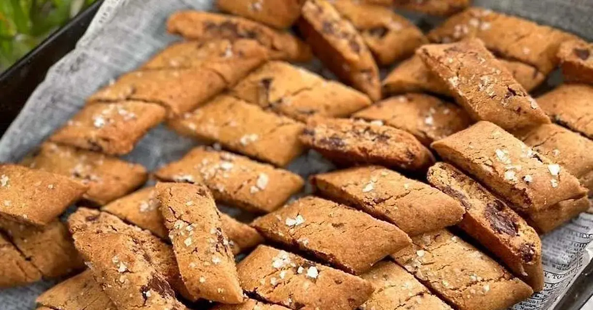 En hög med gyllene kolakakor med chokladbitar och flingsalt. Perfekt för ett enkelt kolakakor recept.