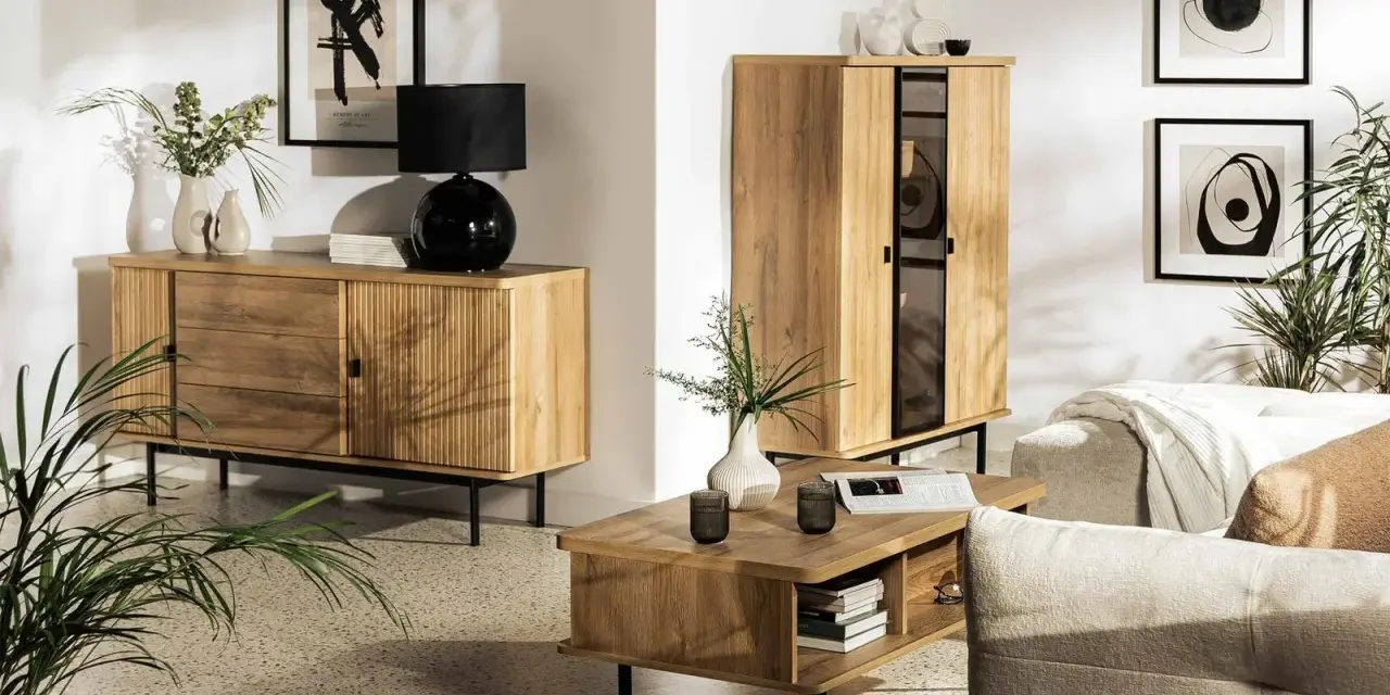 Drewniane meble i subtelne dodatki tworzą przytulną atmosferę w stylu hygge. Wazon z gałązkami i czarna lampa dodają elegancji.