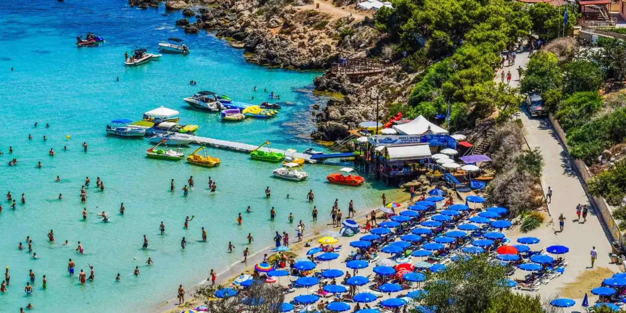Piękna plaża na Cyprze, pełna ludzi kąpiących się i opalających. Czy na Cypr potrzebny jest paszport z Polski? Nie, wystarczy dowód osobisty.