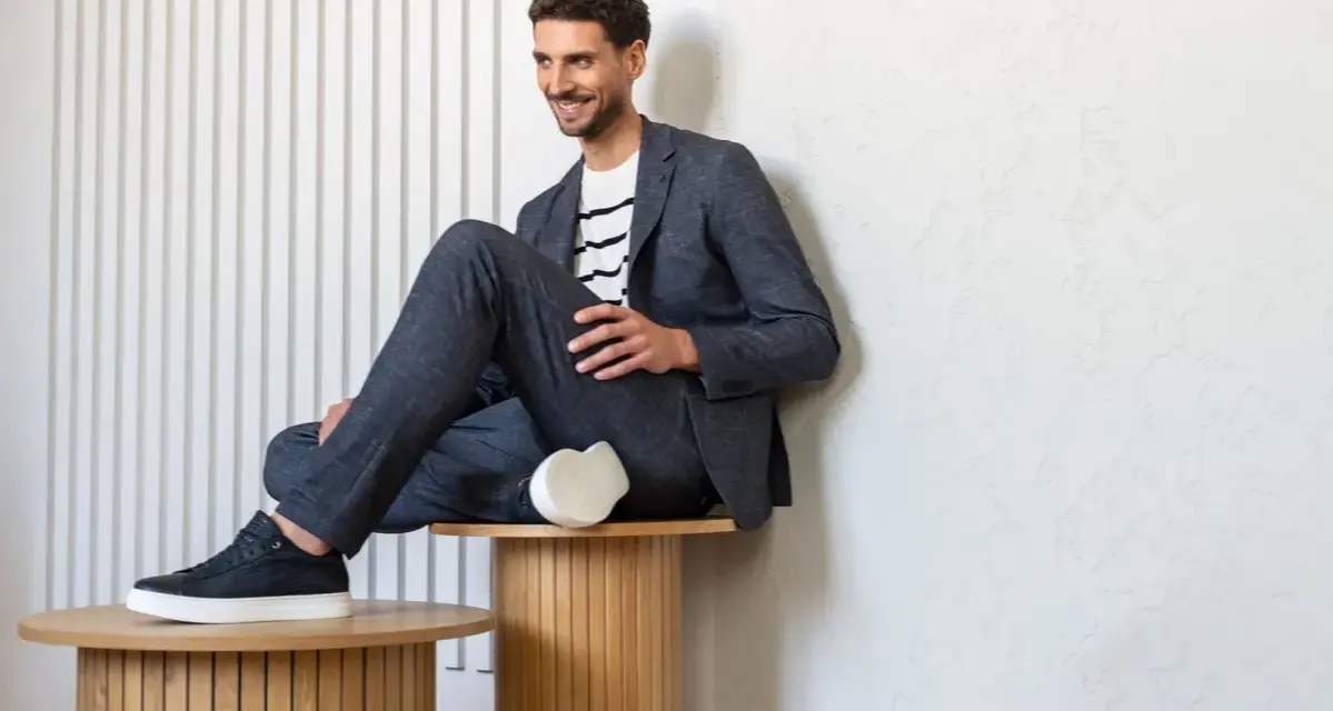 Uśmiechnięty mężczyzna w granatowym garniturze i białej koszulce w paski, idealny przykład dress code smart casual.