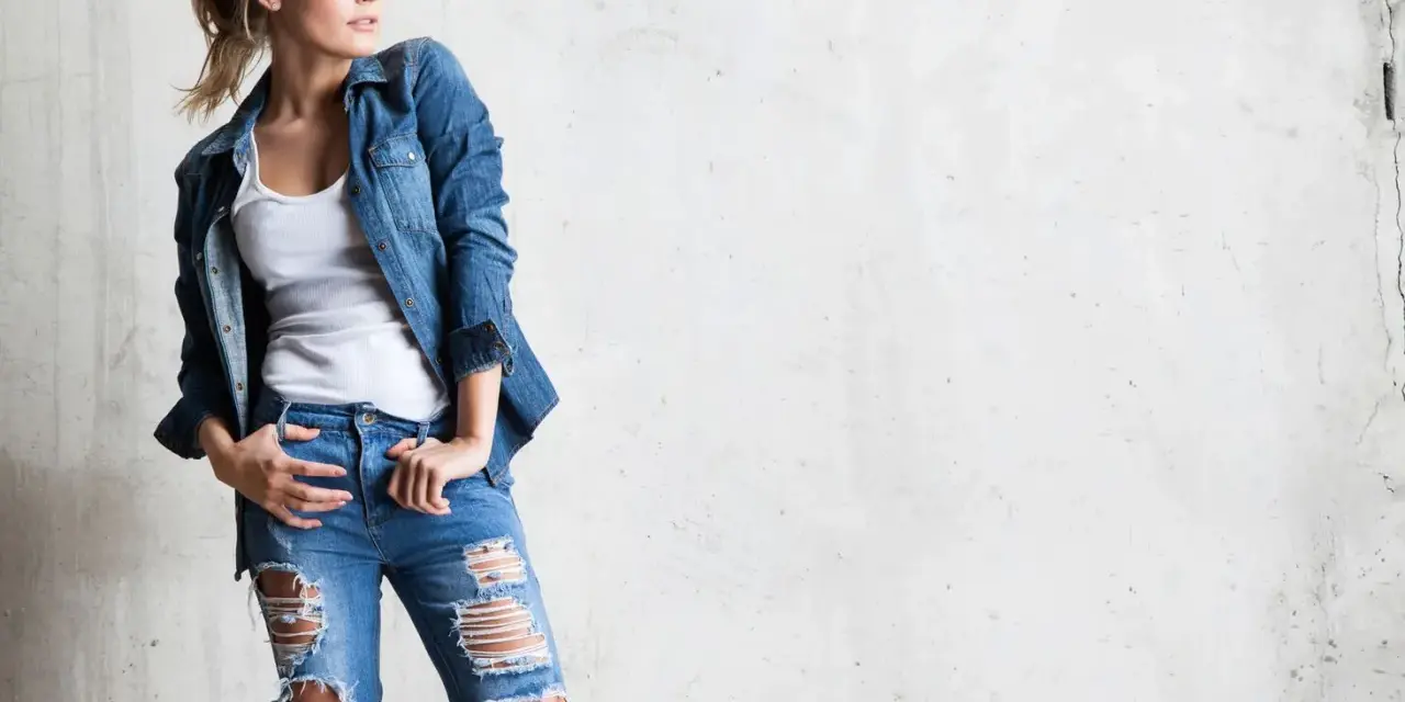Stylowa blondynka w rozdartych jeansach i jeansowej koszuli. Inspiracja, jak nosić koszulę do jeansów.