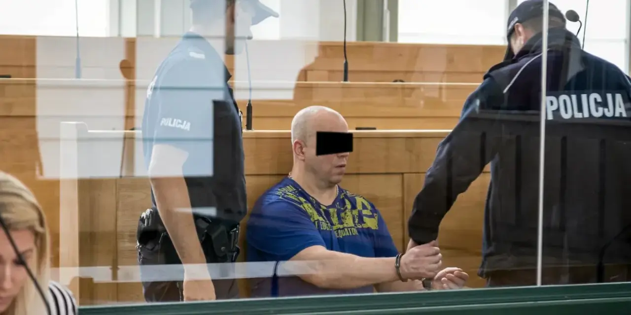 Skruszony gangster w kajdankach, prowadzony przez policjantów w sali sądowej.