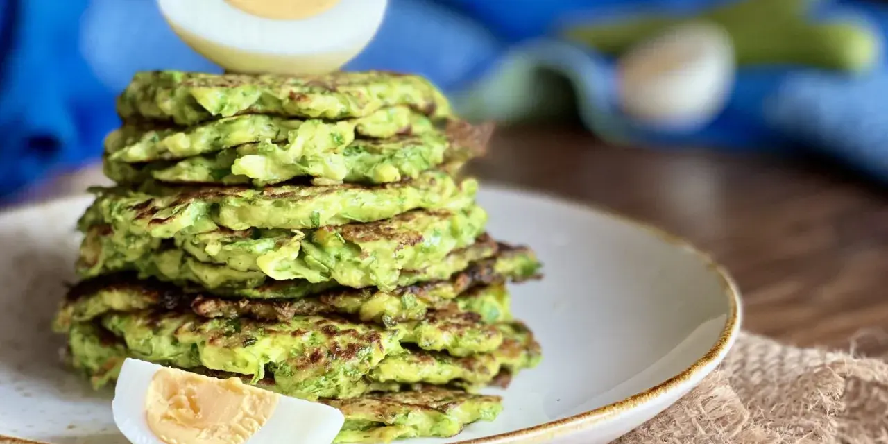 Pila di rosti di zucchine dorati, guarnita con spicchi di uovo sodo. Un piatto leggero e gustoso, perfetto per ogni pasto.