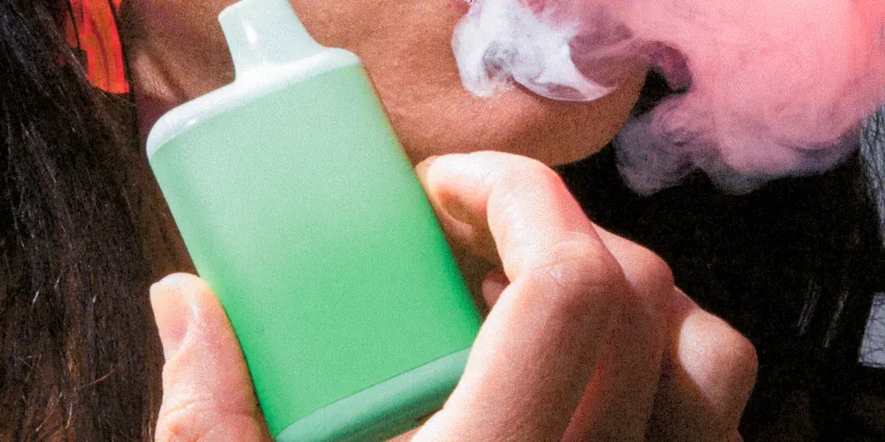 Persona vapeando un dispositivo verde, exhalando vapor. Una imagen que ilustra la diferencia entre vapear y fumar.