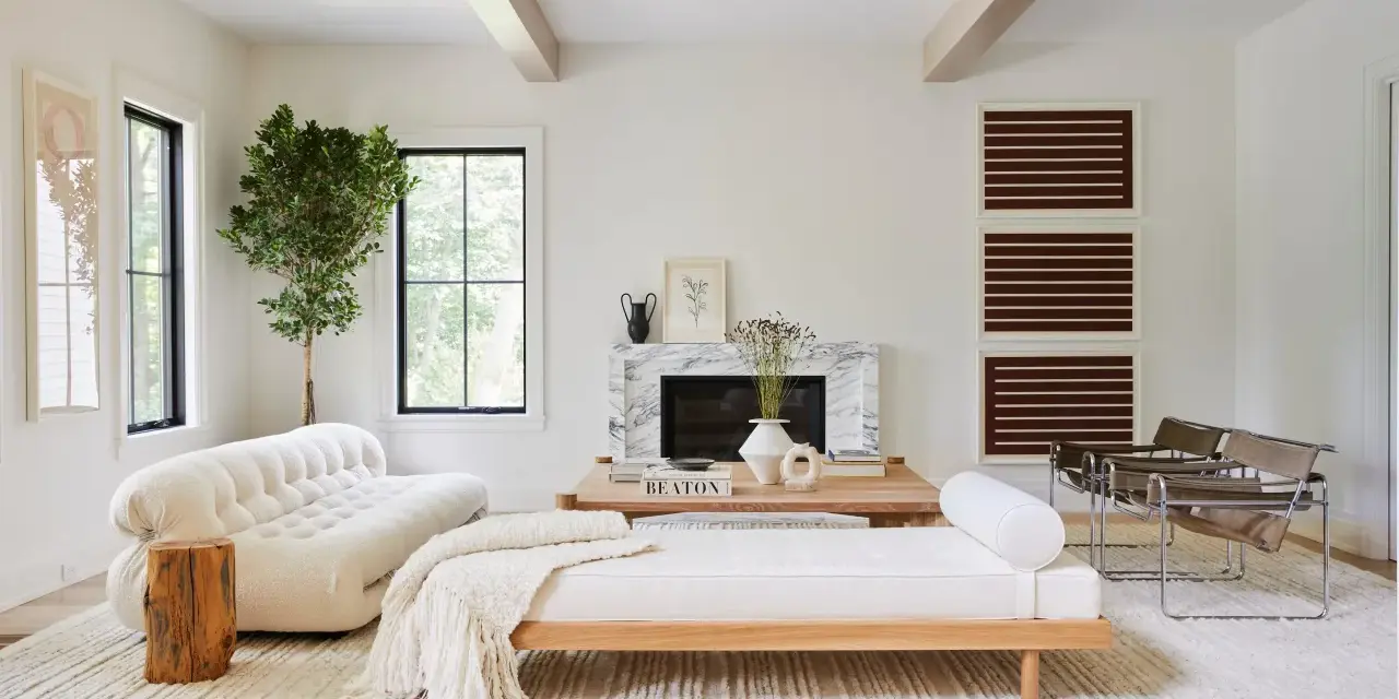 Elegante salón blanco y madera oscura. Sofá blanco texturizado, chaise longue de madera clara, chimenea de mármol y sillas de cuero.