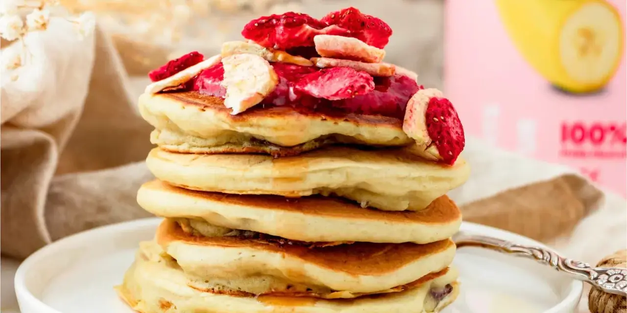 Stapel fluffiger Pfannkuchen mit gefriergetrockneten Erdbeeren und Bananen, perfekt für gesunde Snacks selber machen.
