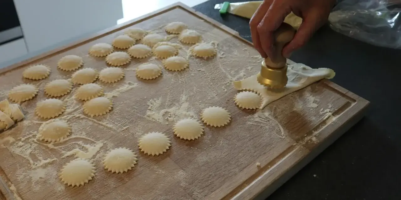Ręcznie robione ciasto na ravioli, wycinane okrągłym wykrawaczem. Widać wiele gotowych krążków na desce.