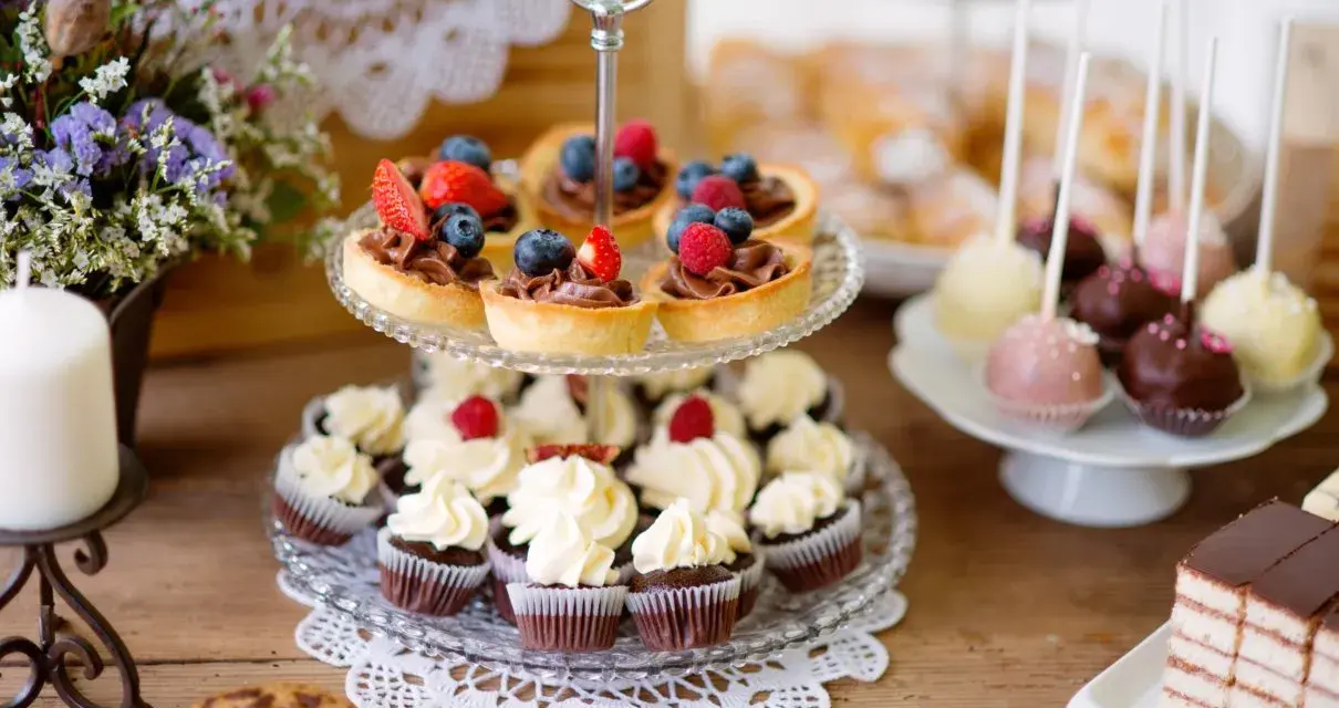 Stół z ciastkami, babeczkami, tartaletkami z owocami i cake pops.