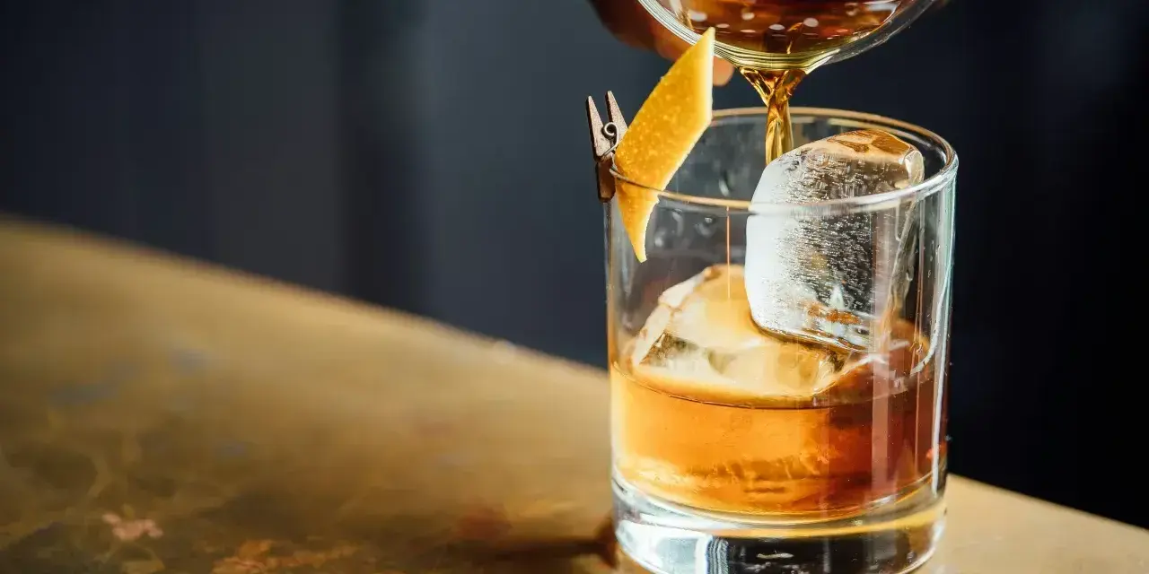 Idealny wieczór: nalewanie whisky z colą do szklanki z lodem i skórką pomarańczy.