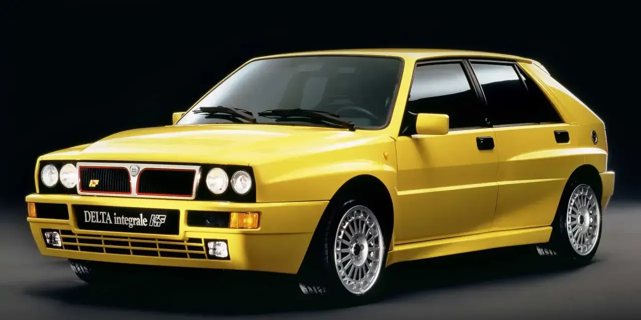 Żółta Lancia Delta Integrale HF z lat 90. na czarnym tle, z charakterystycznym grillem i felgami.