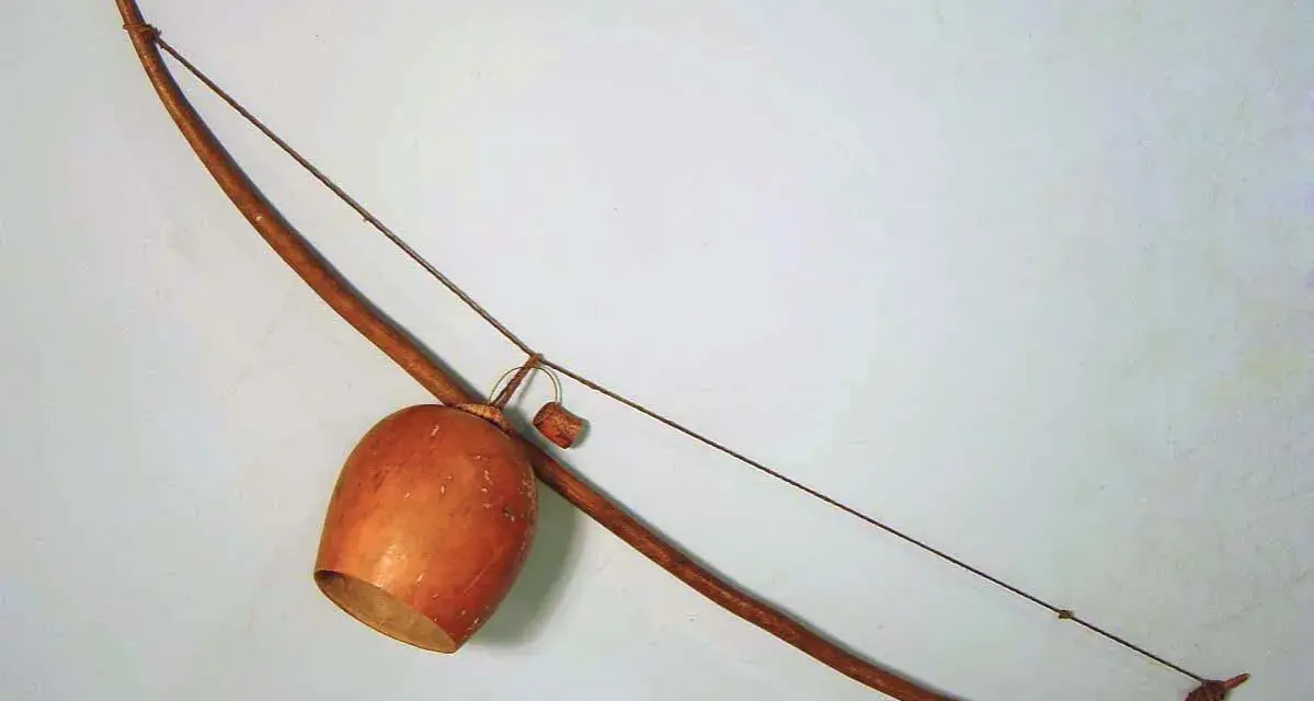Drewniany łuk muzyczny instrument z tykwą jako pudłem rezonansowym.
