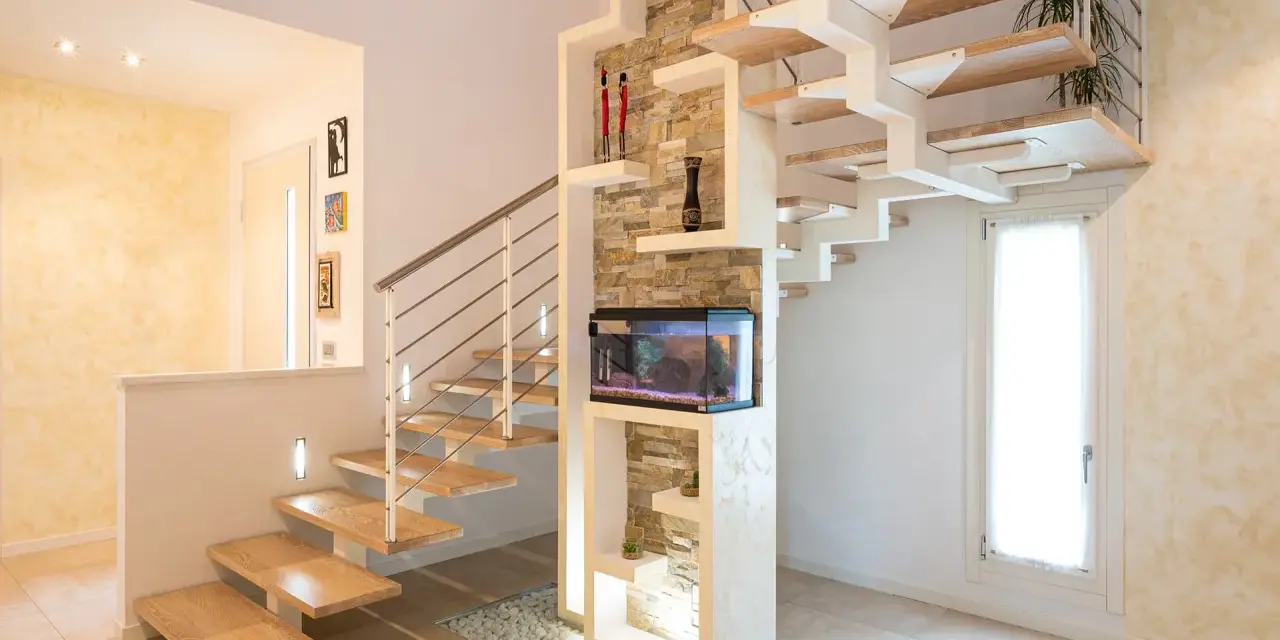 Moderna scala interna in legno e metallo, con acquario integrato e decorazioni in pietra. Un esempio di design che valorizza il costo scala interna.