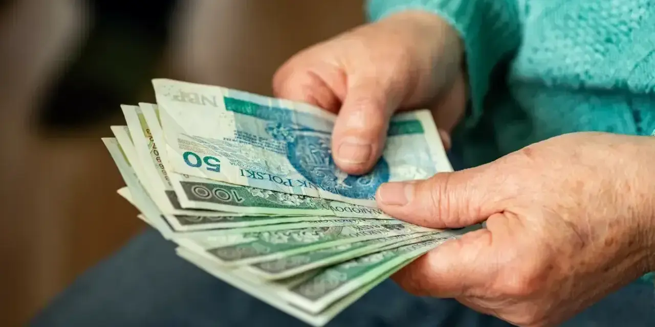 Dłonie starszej osoby liczą banknoty. Zastanawiasz się, ile wynosi dodatek do emerytury za warunki szkodliwe?