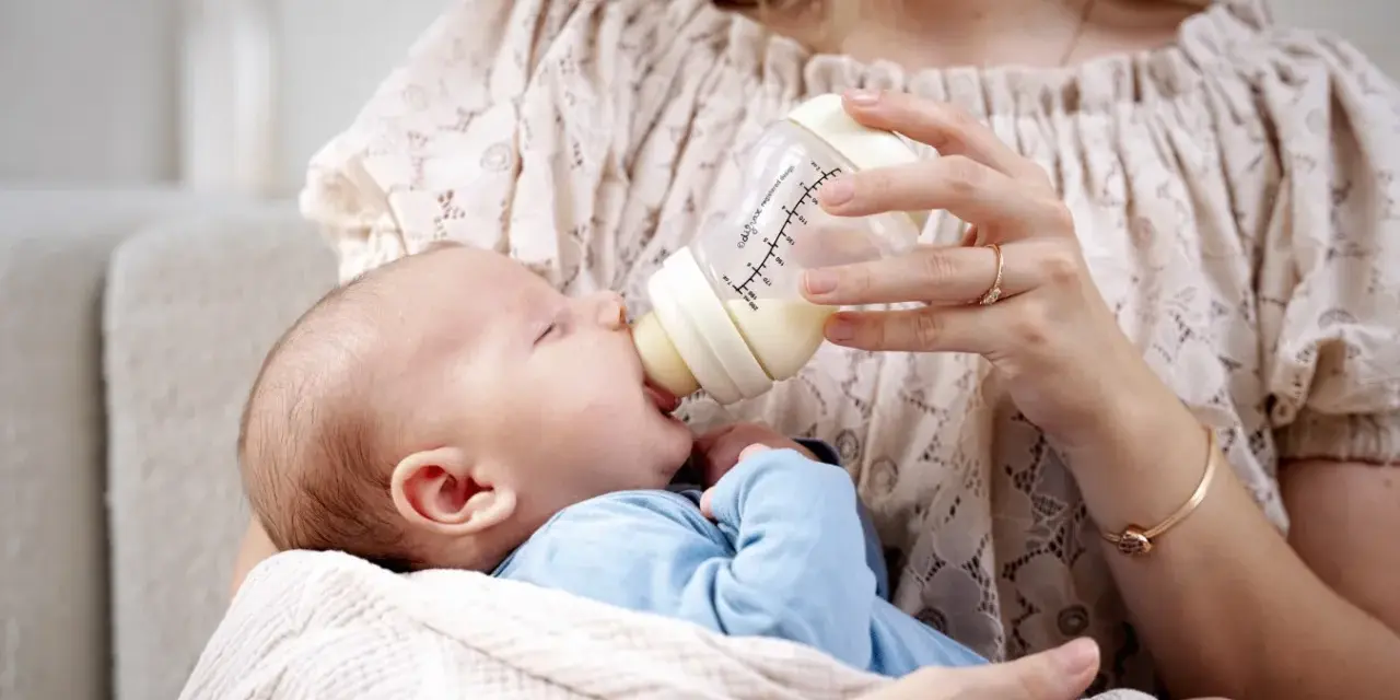 Mama karmi maluszka z butelki, która może być najlepszą butelką antykolkową dla noworodka.
