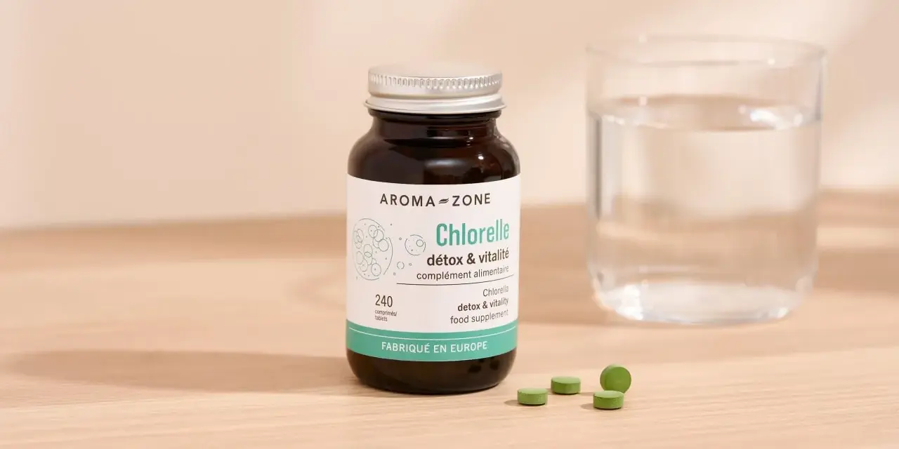 Bouteille de chlorelle Aroma-Zone, 240 comprimés. Pour une cure détox et vitalité, combien de temps faut-il ? Verre d'eau à côté.