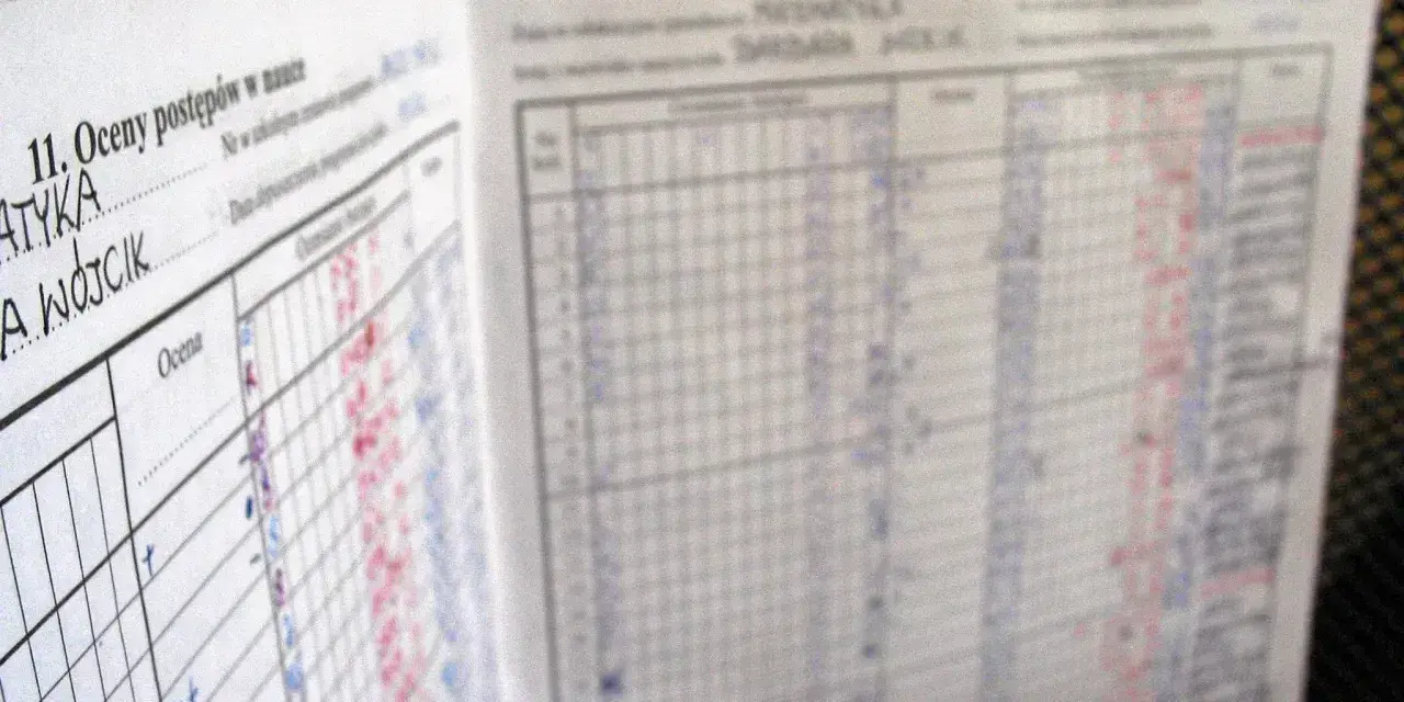 Strona dziennika z wpisanymi ocenami postępów w nauce. Widać rubryki z przedmiotami i wpisy ocen, niektóre czerwone, inne niebieskie.
