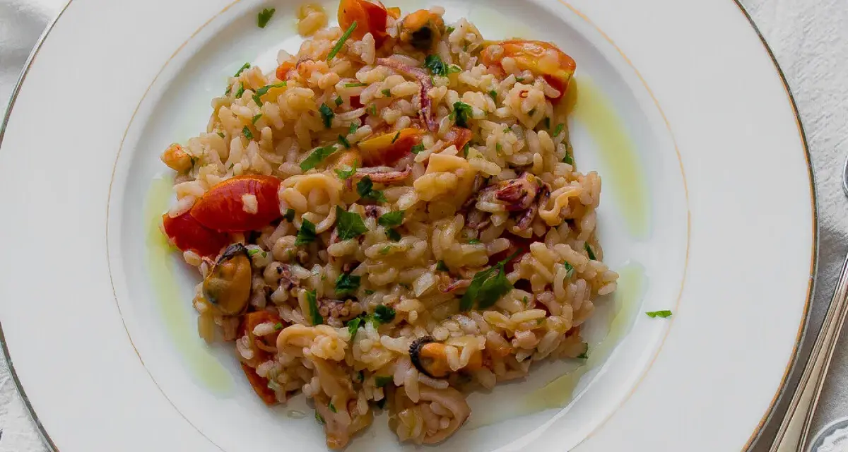 Pyszne risotto z owocami morza, z pomidorkami i natką pietruszki, polane oliwą.