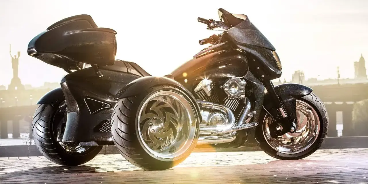Czarny, lśniący motocykl trzykołowy z chromowanymi felgami, gotowy do podróży.
