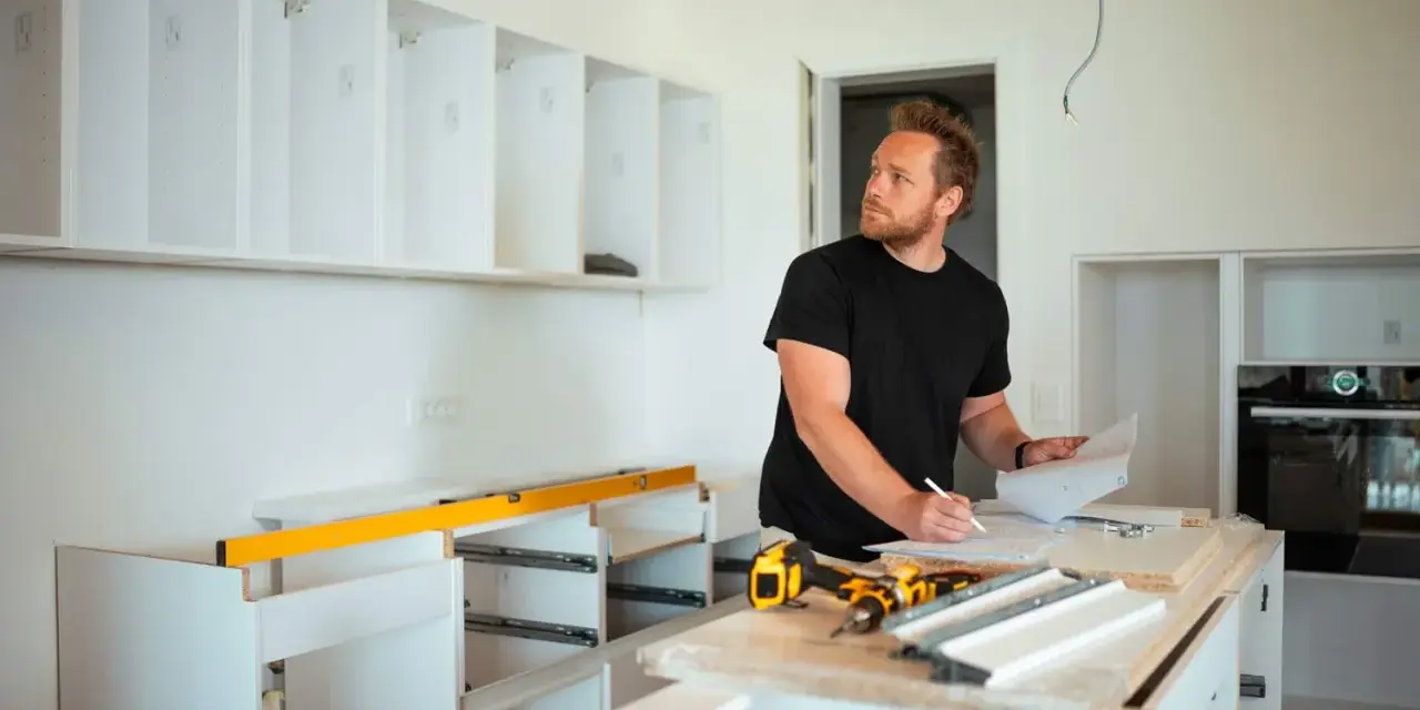 Mężczyzna planuje, jak zabudować przestrzeń nad szafkami kuchennymi, analizując projekt.