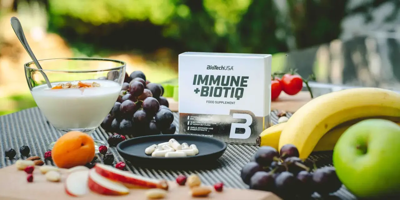 Zielone jabłko, winogrona, banany i jogurt z owocami. Obok suplement diety Immune+Biotiq. Idealne na keto.