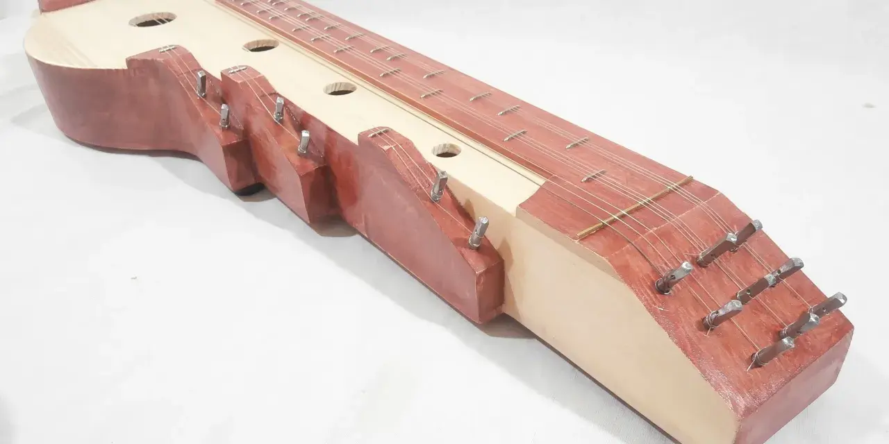 Drewniana cytra instrument z wieloma strunami i otworami rezonansowymi.