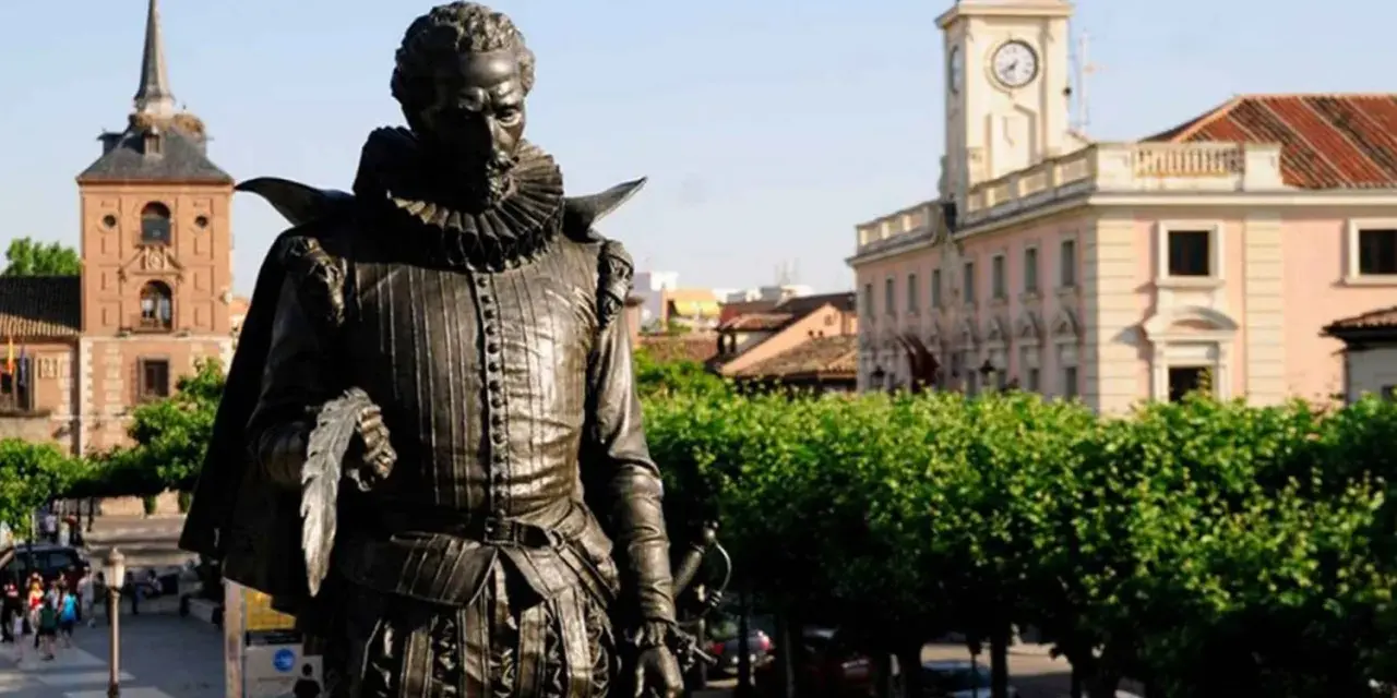 Pomnik Cervantesa w Alcalá de Henares, z ratuszem i wieżą zegarową w tle.