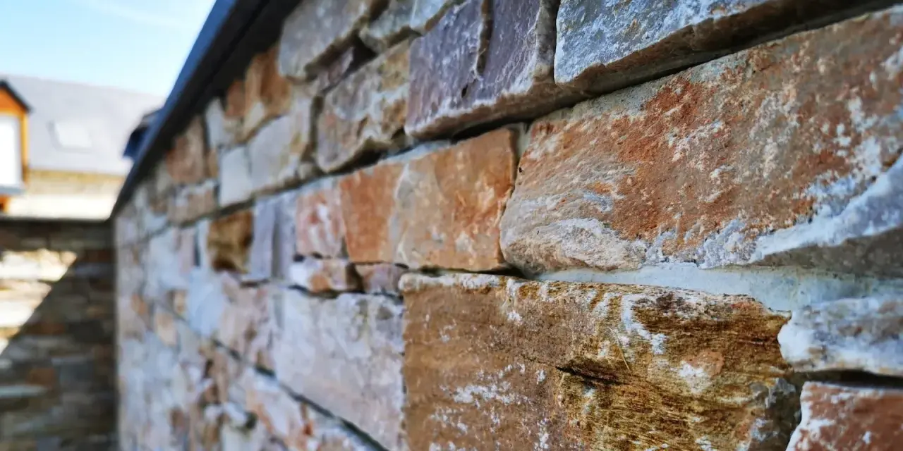 Gros plan sur une pose de pierre de parement extérieur aux teintes chaudes et naturelles, créant une texture rustique et élégante.