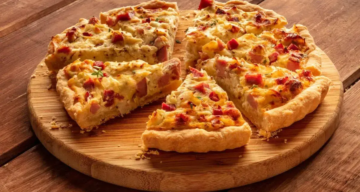 Fette di torta salata patate e salsiccia dorata e invitante, servite su un tagliere di legno.