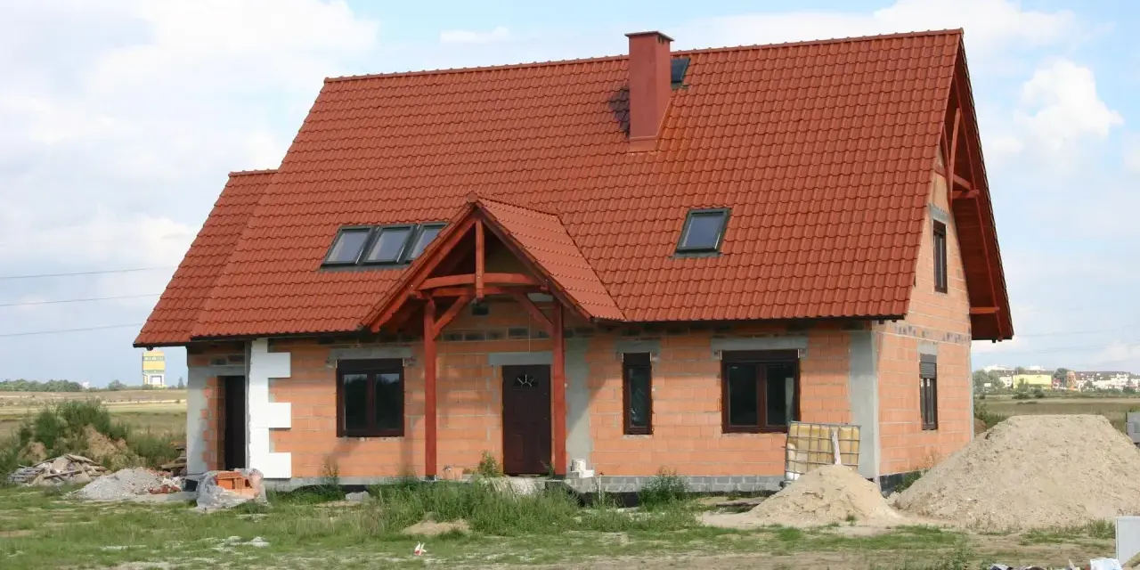 Dom w budowie z czerwonym dachem i oknami dachowymi. Wnętrze z potencjałem na wysoki, **sufit katedralny**.
