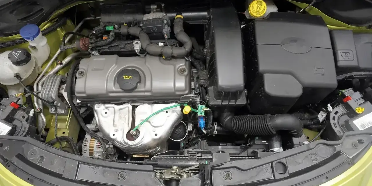 Silnik Peugeot 207, widok z góry. Widać elementy układu dolotowego, pokrywę zaworów i alternator.