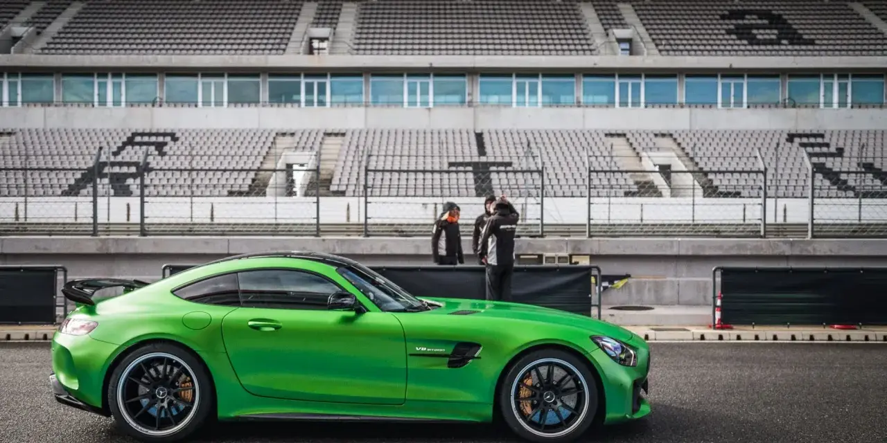 Zielony Mercedes GTR na torze wyścigowym, gotowy do jazdy. Za nim puste trybuny stadionu.