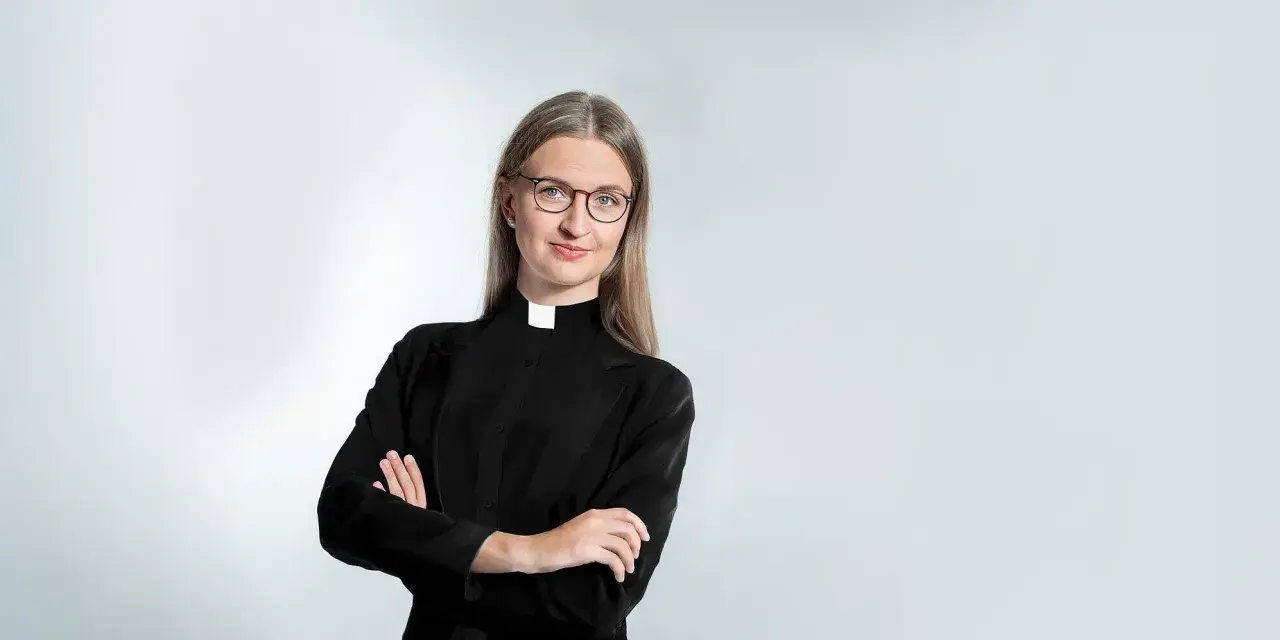 Eine Frau mit Brille und Kragen, die zeigt, dass Pfarrer Beamte sind.