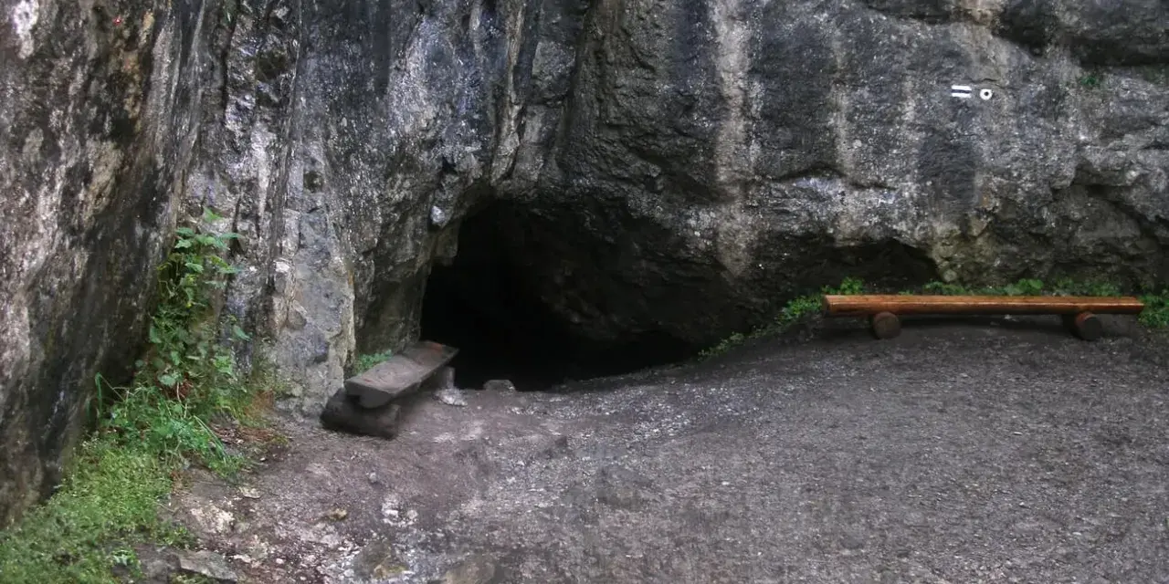 Wejście do jaskini na trasie "Dolina ku dziurze". Obok ławka i kamienne schodki.