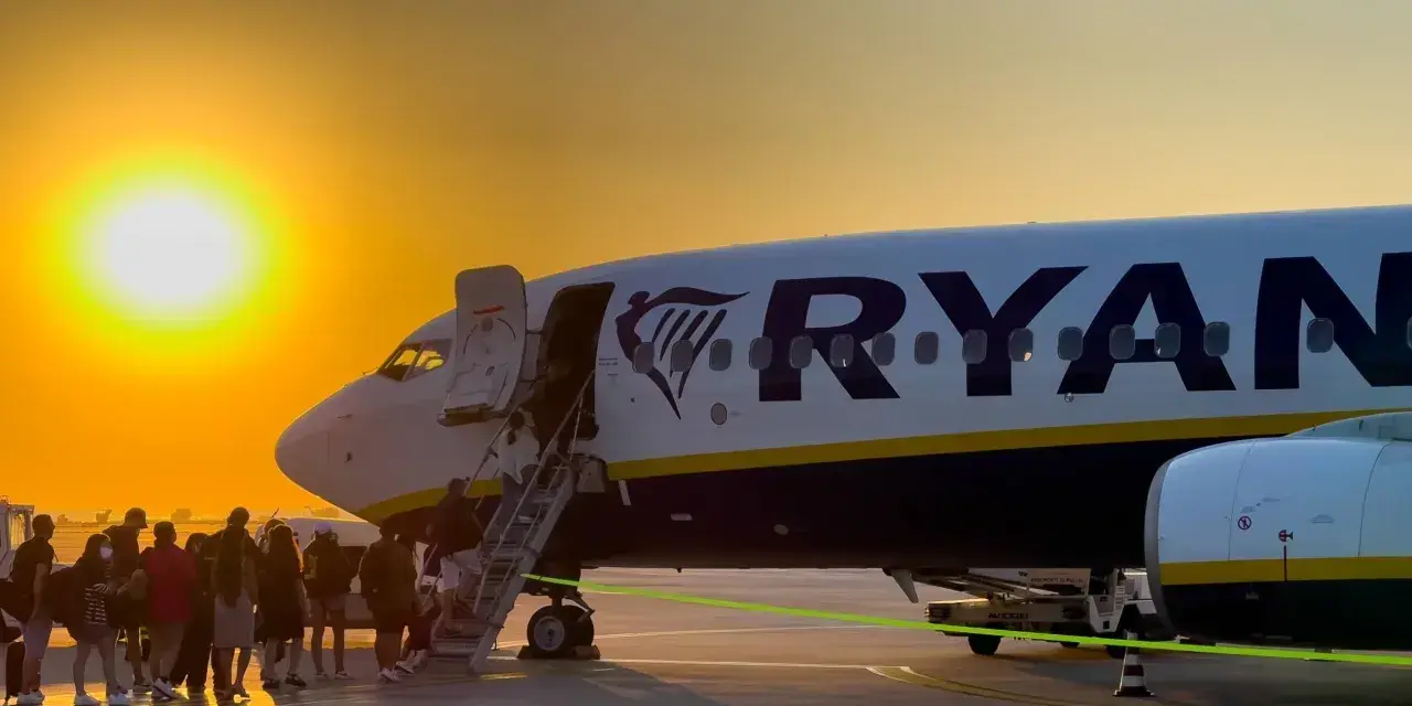 Ryanair loty za 1 zł – pasażerowie wsiadają do samolotu o zachodzie słońca.