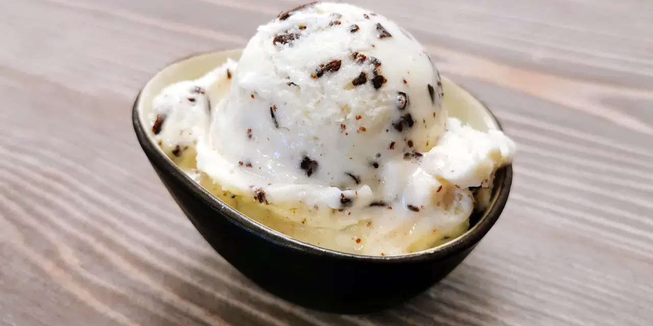 Ein Löffel cremiges Stracciatella-Eis mit zarten Schokoladenstückchen in einer Schale.