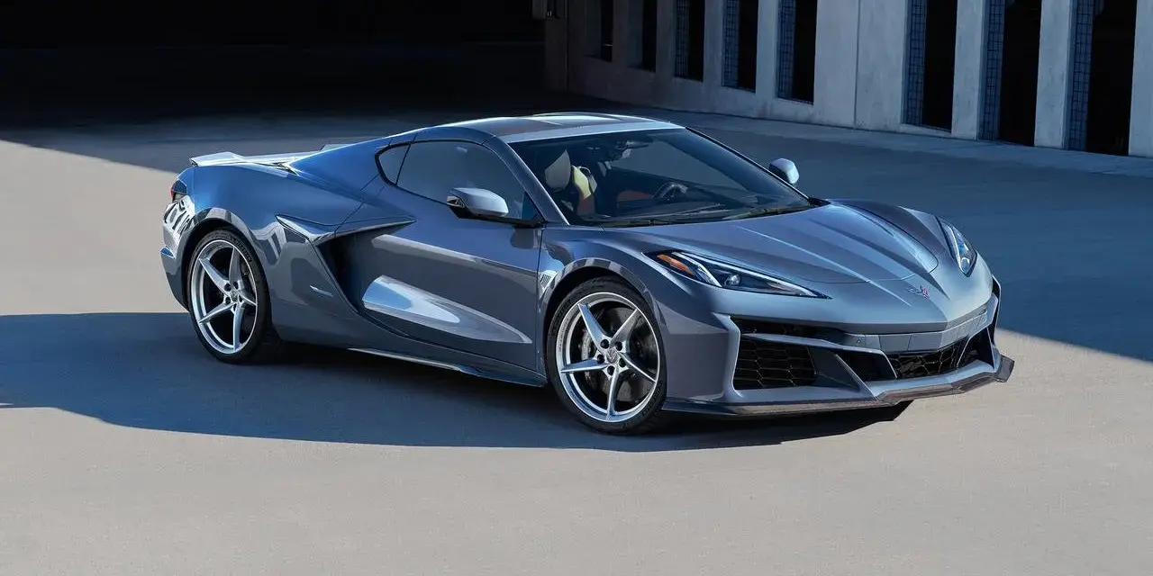 Szary Chevrolet Corvette Stingray z nowoczesnym designem, zaparkowany na tle betonowej architektury.