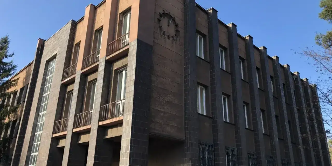 Imponujący budynek w stylu modernizm architektura, z ciemnymi płytkami i jasnymi akcentami, ozdobiony zegarem.