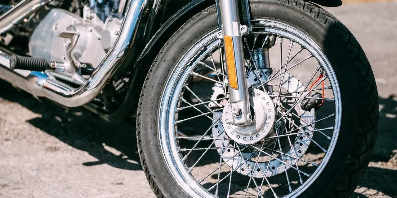Zbliżenie na koło motocykla z widocznym silnikiem i chromowanymi elementami.