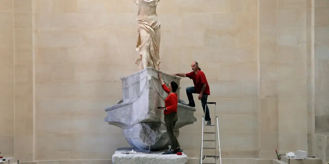 Deux personnes travaillent sur la Victoire de Samothrace, dont la signification symbolise la victoire et la liberté.
