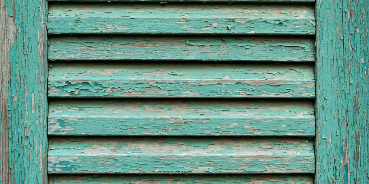 Persiane in legno fai da te con vernice verde acqua scrostata, che rivela il legno grezzo sottostante.