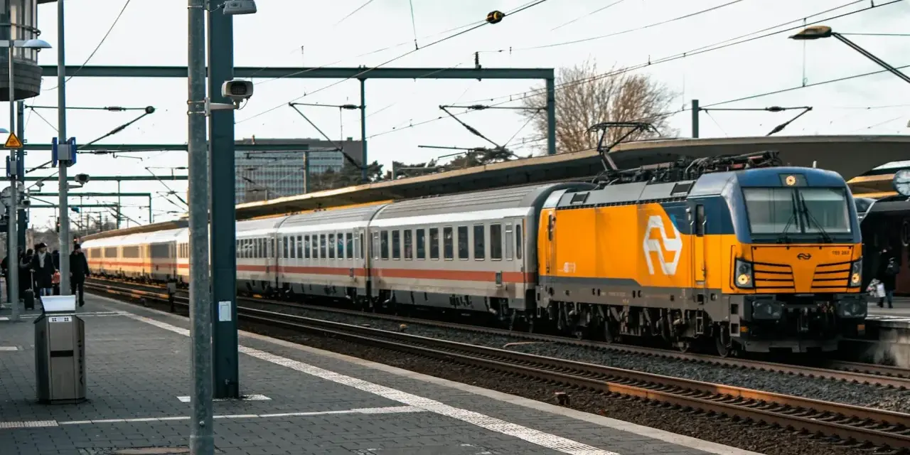 Pociąg Berlin Warszawa Express z żółto-niebieską lokomotywą na peronie.