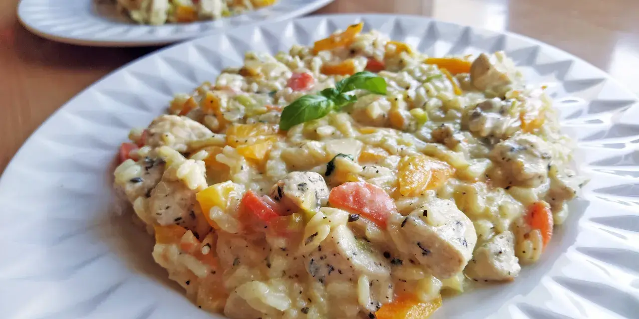 Pyszne risotto z kurczakiem, papryką i ziołami na białym talerzu. Drugie danie w tle.