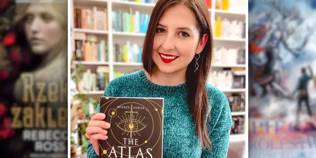 Uśmiechnięta kobieta trzyma książkę "The Atlas Six". W tle widać półki z książkami, w tym inne serie książek fantasy.