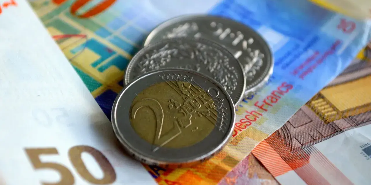 Münzen und Banknoten, darunter ein 2-Euro-Stück und Schweizer Franken. So lässt sich der Urlaub auszahlen!