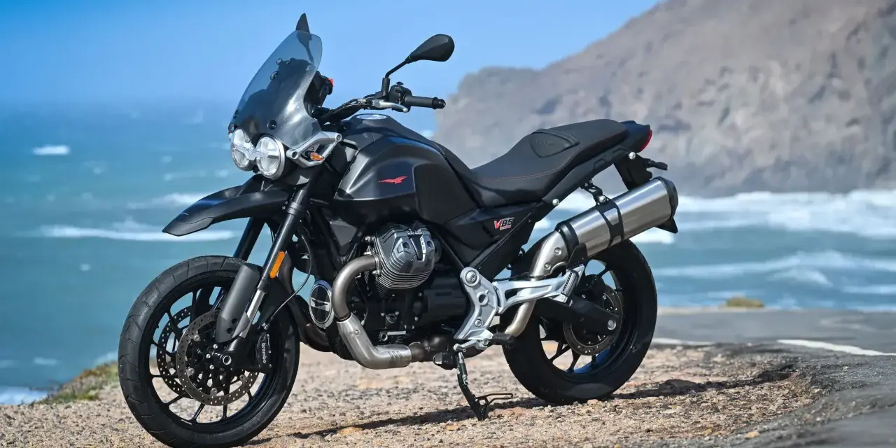 Moto Guzzi V85TT nera, pronta per esplorare, con la sua velocità massima che promette avventure sul mare.