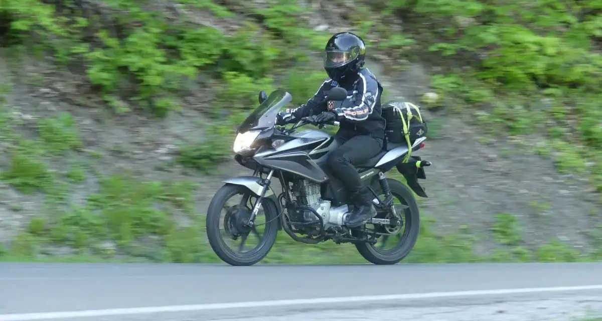 Motocyklista pokonuje zakręt na przełęczy Przysłup, otoczony zielenią górskich zboczy.