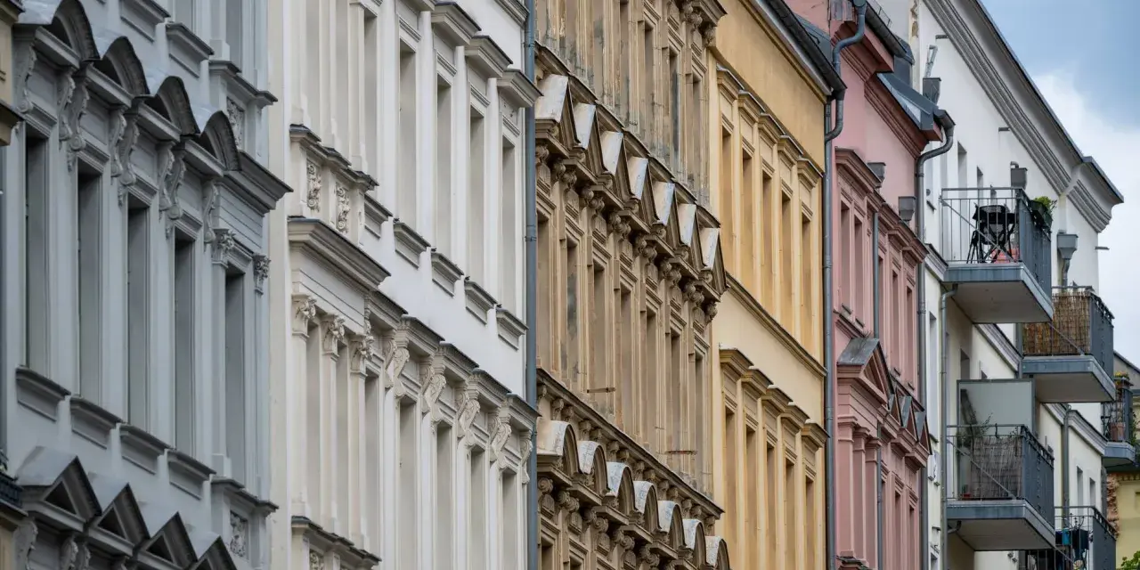 Reihenhausfassaden in verschiedenen Farben, von Grau über Beige bis Rosa. Ein Blick auf den m2 preis wohnung in dieser Gegend.