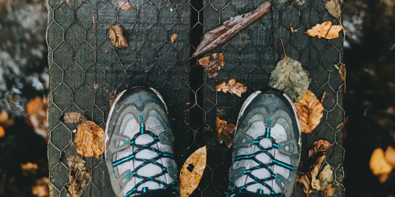 Scarpe in Gore-Tex donna pronte per un'avventura autunnale su un ponte di legno coperto di foglie.